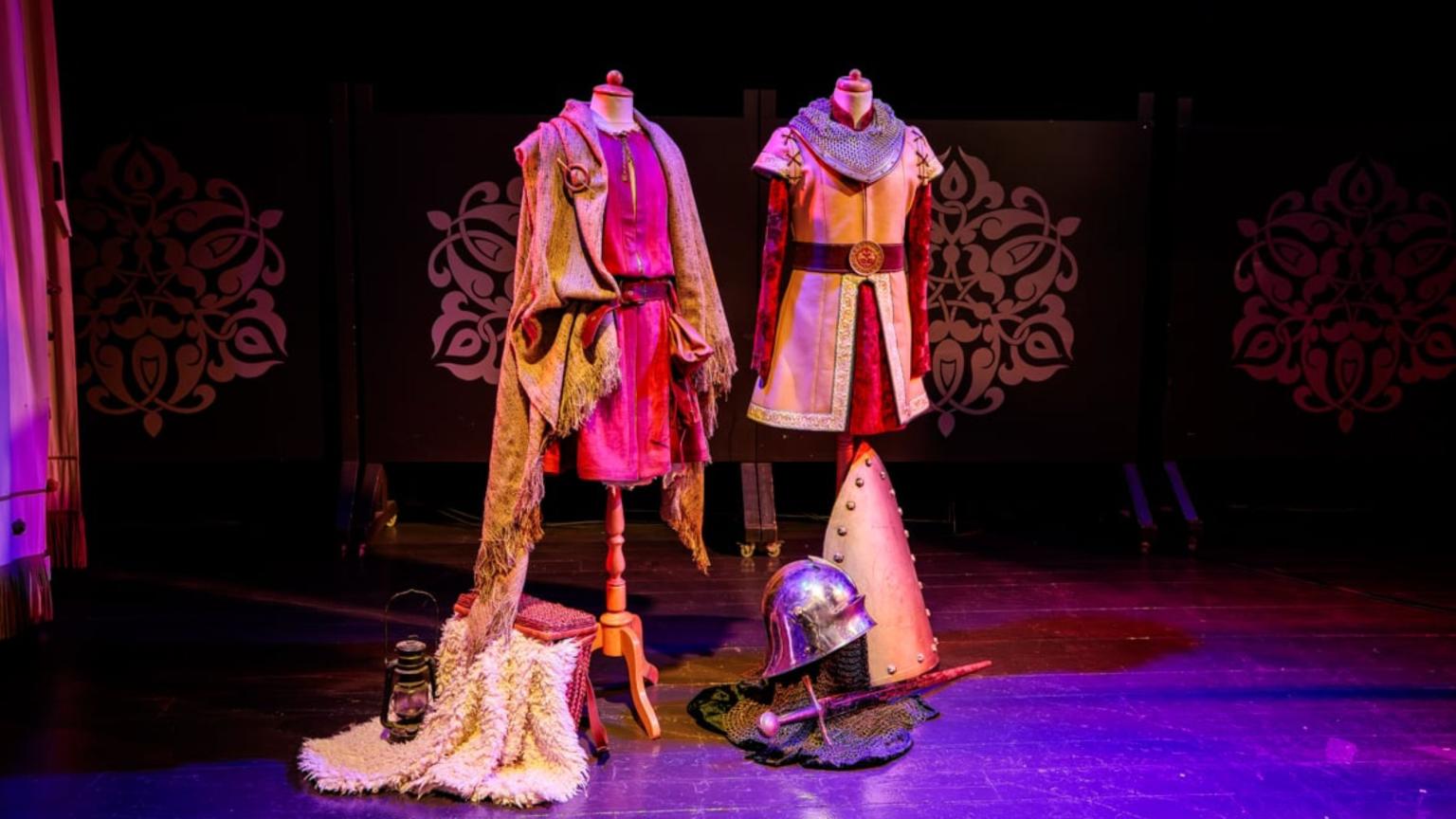 Twee middeleeuwse kostuums op paspoppen op een theaterpodium