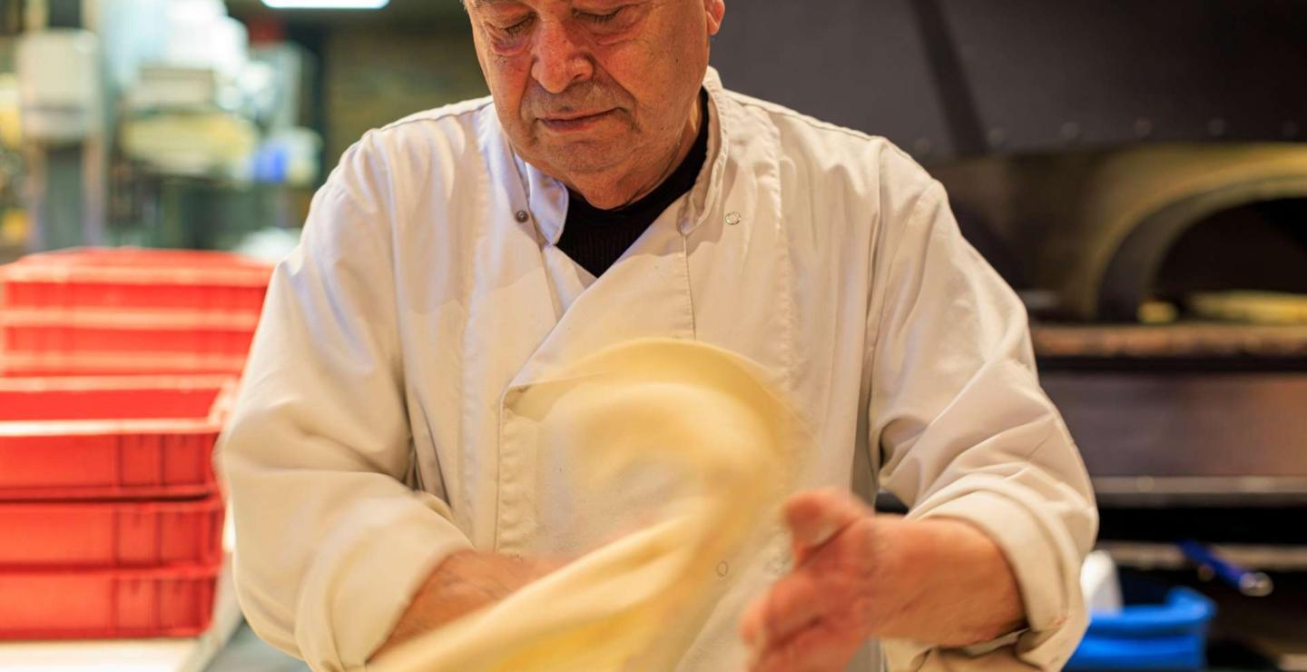 Pizzabakker stretch het deeg voor de pizza