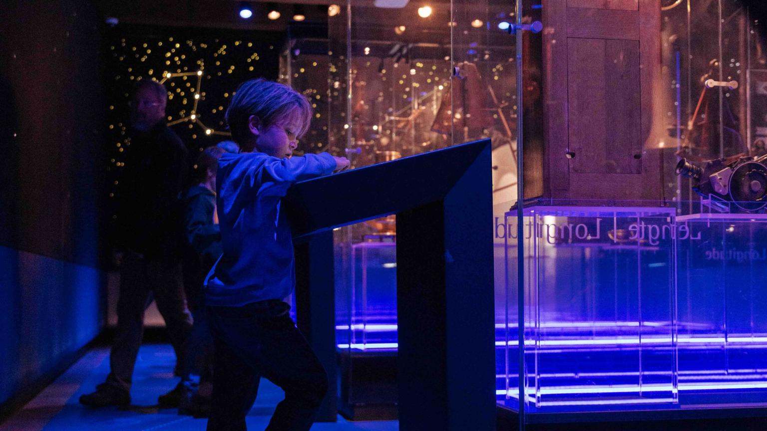 Jongen gebruikt een interactieve tafel om meer te leren over navigeren op zee aan de hand van sterren.