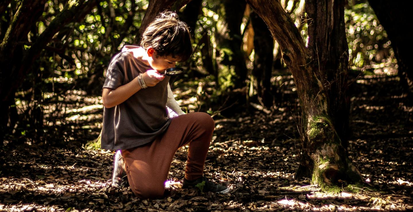 Kind met een vergrootglas op onderzoek in het bos