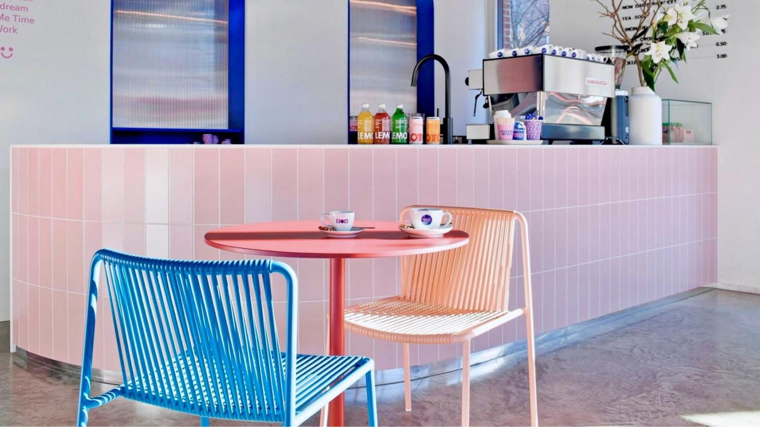 Modern roze café-interieur met tafel, stoelen en twee kopjes koffie|playtix