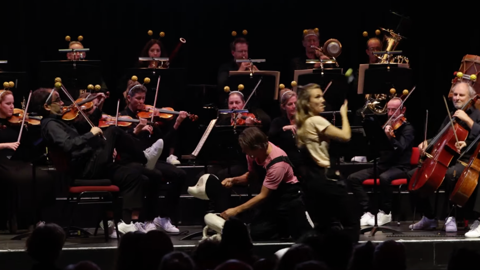 Live-voorstelling van Muk en het Orkest met puppeteers op het podium en een volledig orkest dat meespeelt.
