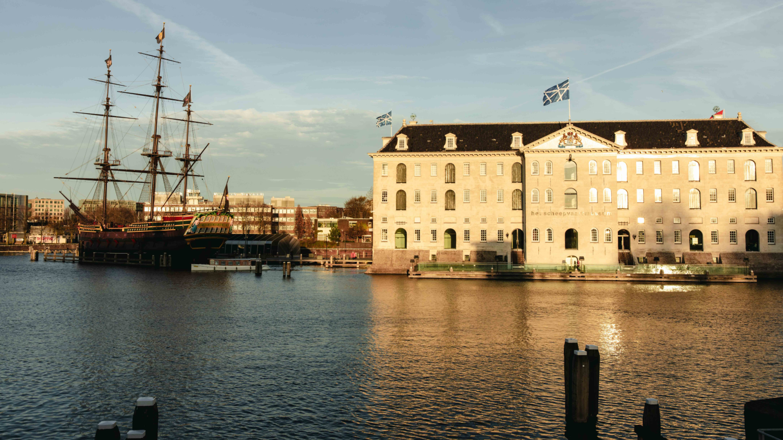 Het VOC-schip Amsterdam aangemeerd voor Het Scheepvaartmuseum, met het museumgebouw en het schip samen in één overzicht.