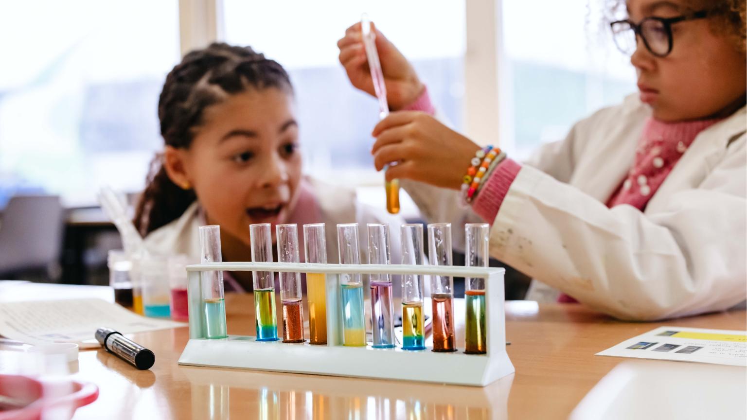 Kinderen in labjassen werken met reageerbuizen en kleurrijke vloeistoffen