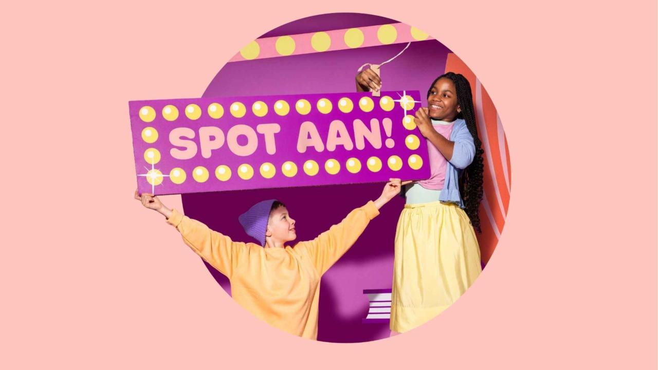 twee kinderen in een theater houden een bord imhoog met Spot aan
                