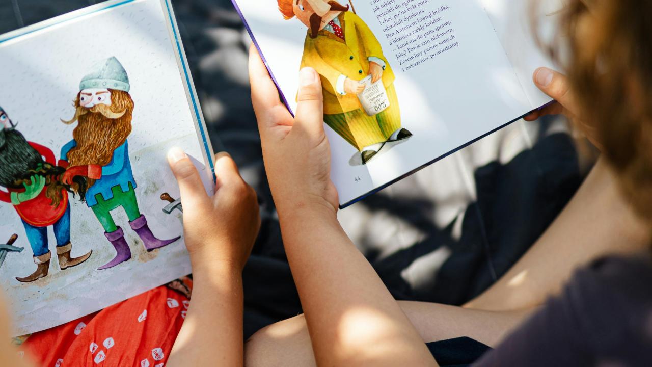 Two children are reading a picture book.
                