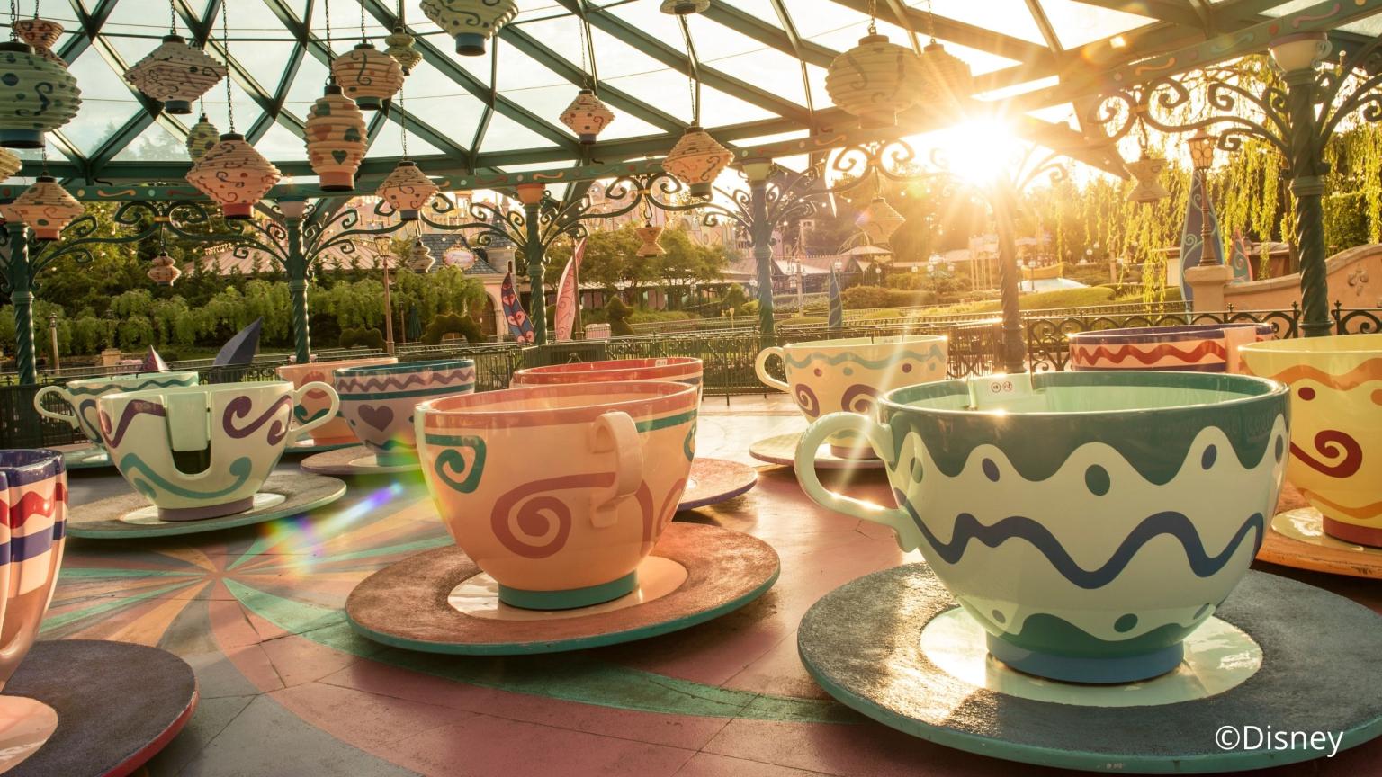 Colorful teacup ride at Disneyland with sunlight shining through a glass canopy