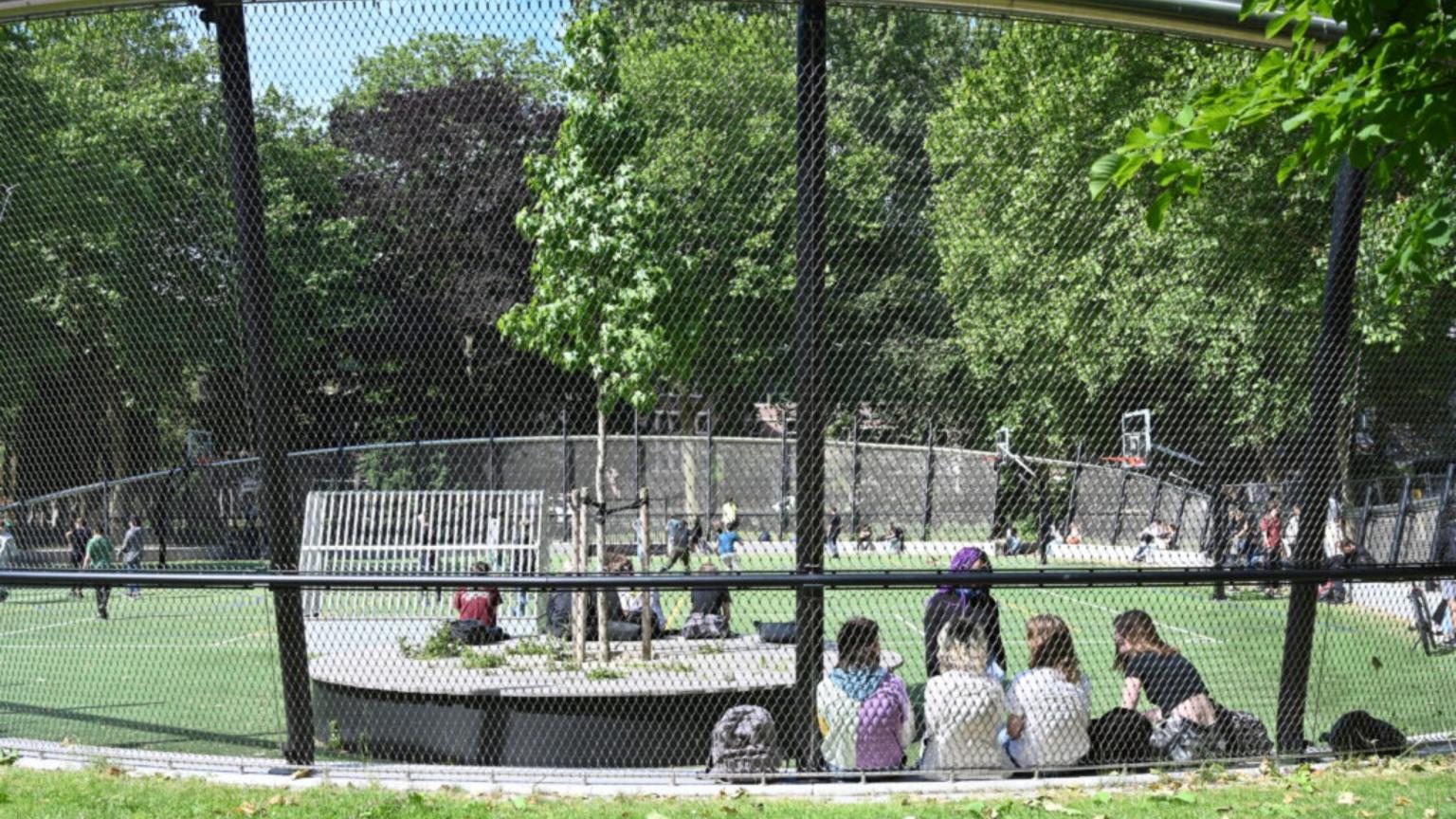 Children are sitting by the sports field in Oosterpark in Amsterdam.