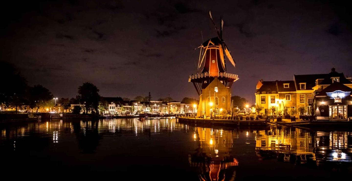 Verlichte molen aan het water in de nacht
