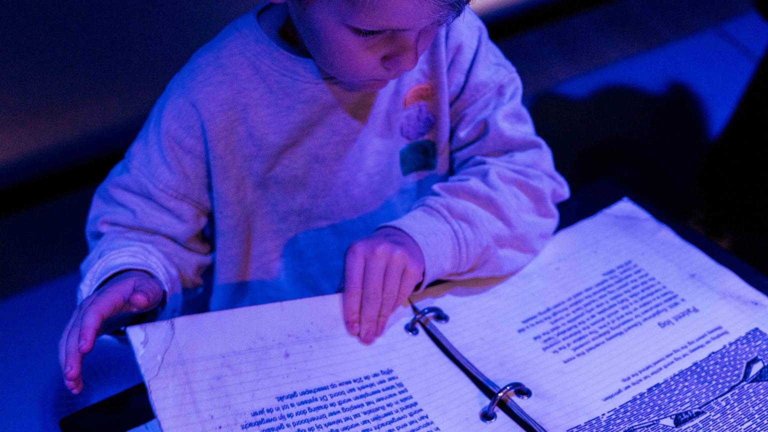 Jongen bladert in een interactief boek over navigatie en sterren in Het Scheepvaartmuseum.