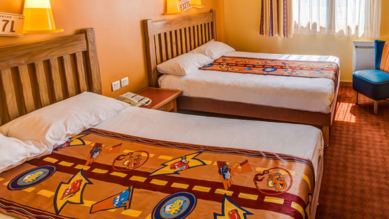 Family-friendly hotel room at Disney Hotel Santa Fe with colorful Cars-themed bedding.