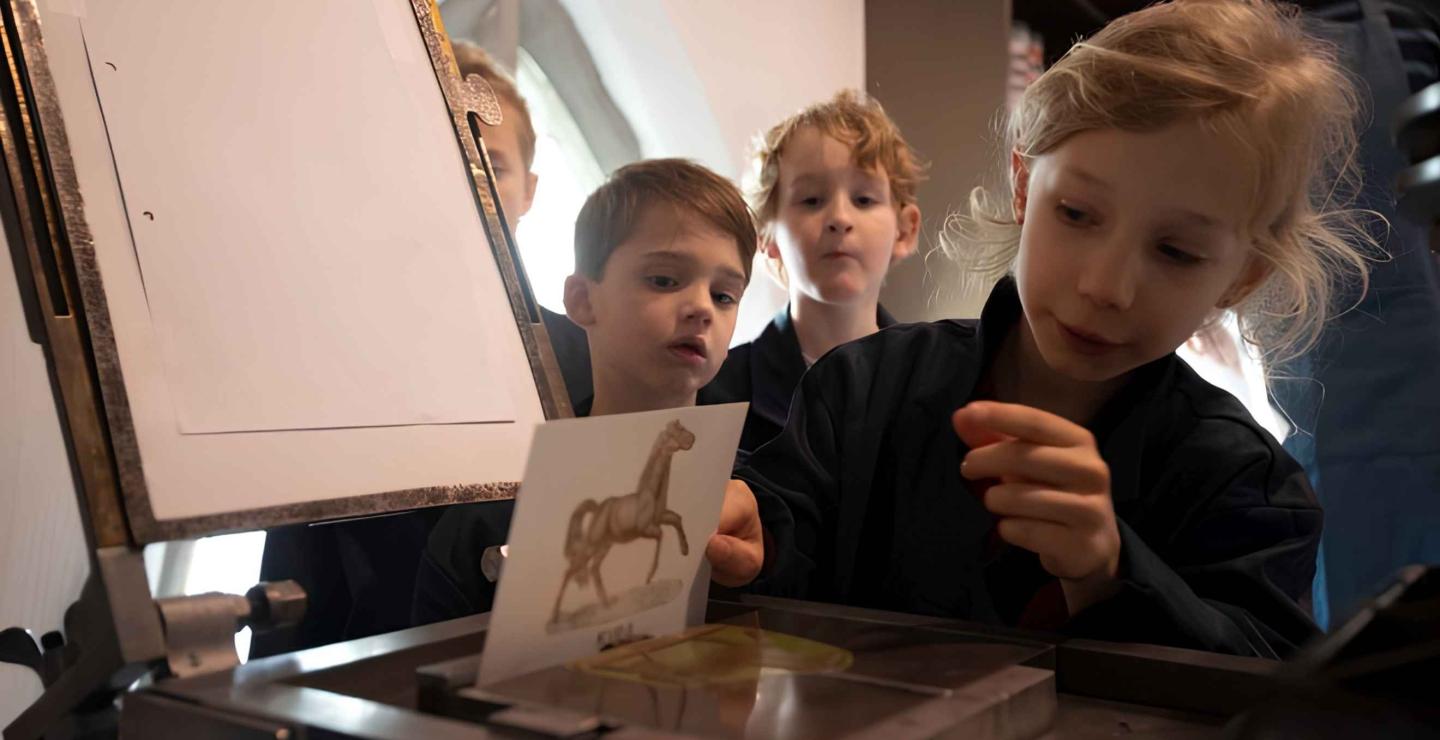 Kinderen drukken een kaartje met een traditionele drukpers