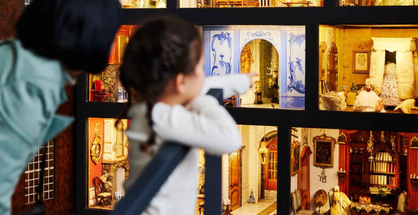 Kind zoekt met een verrekijker in een verlicht poppenhuis