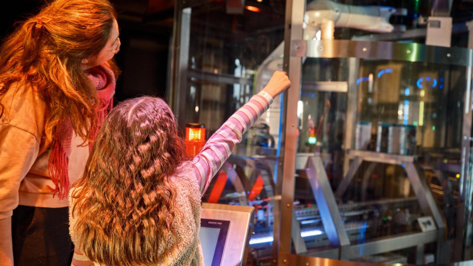 Kind en ouder bedienen een machine tijdens de interactieve ervaring in The Chocolate Factory Veghel