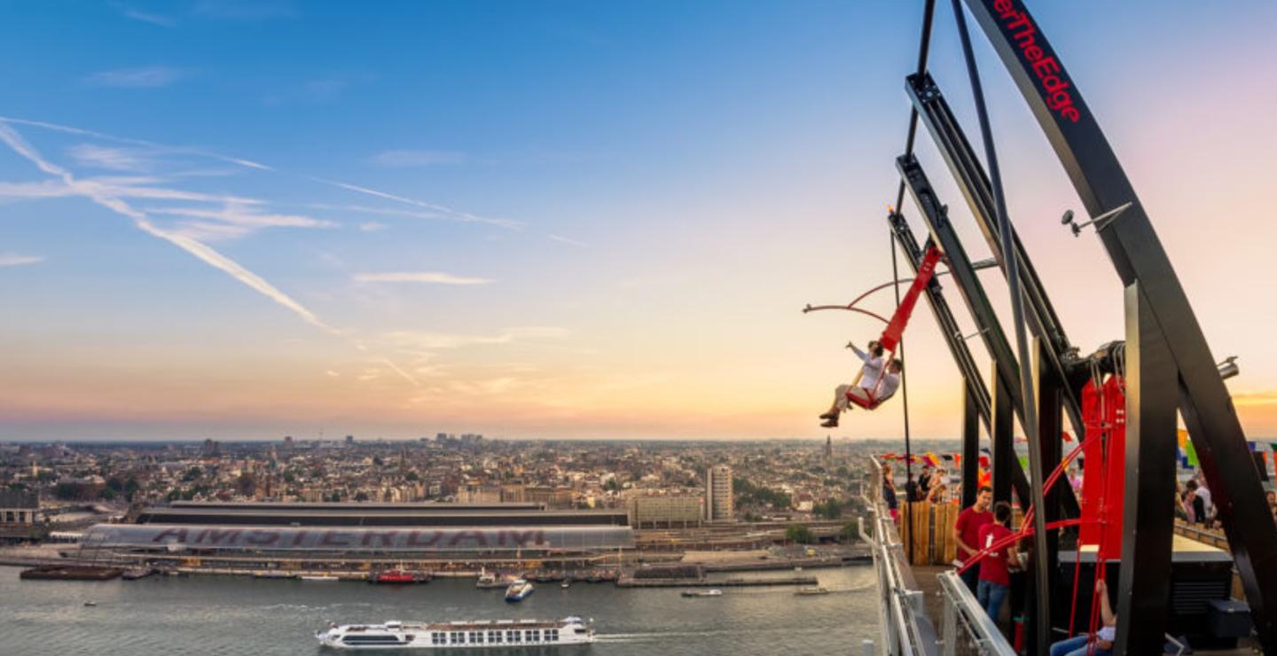 Gezin op de schommel Over The Edge bij A’DAM Lookout met uitzicht over Amsterdam.