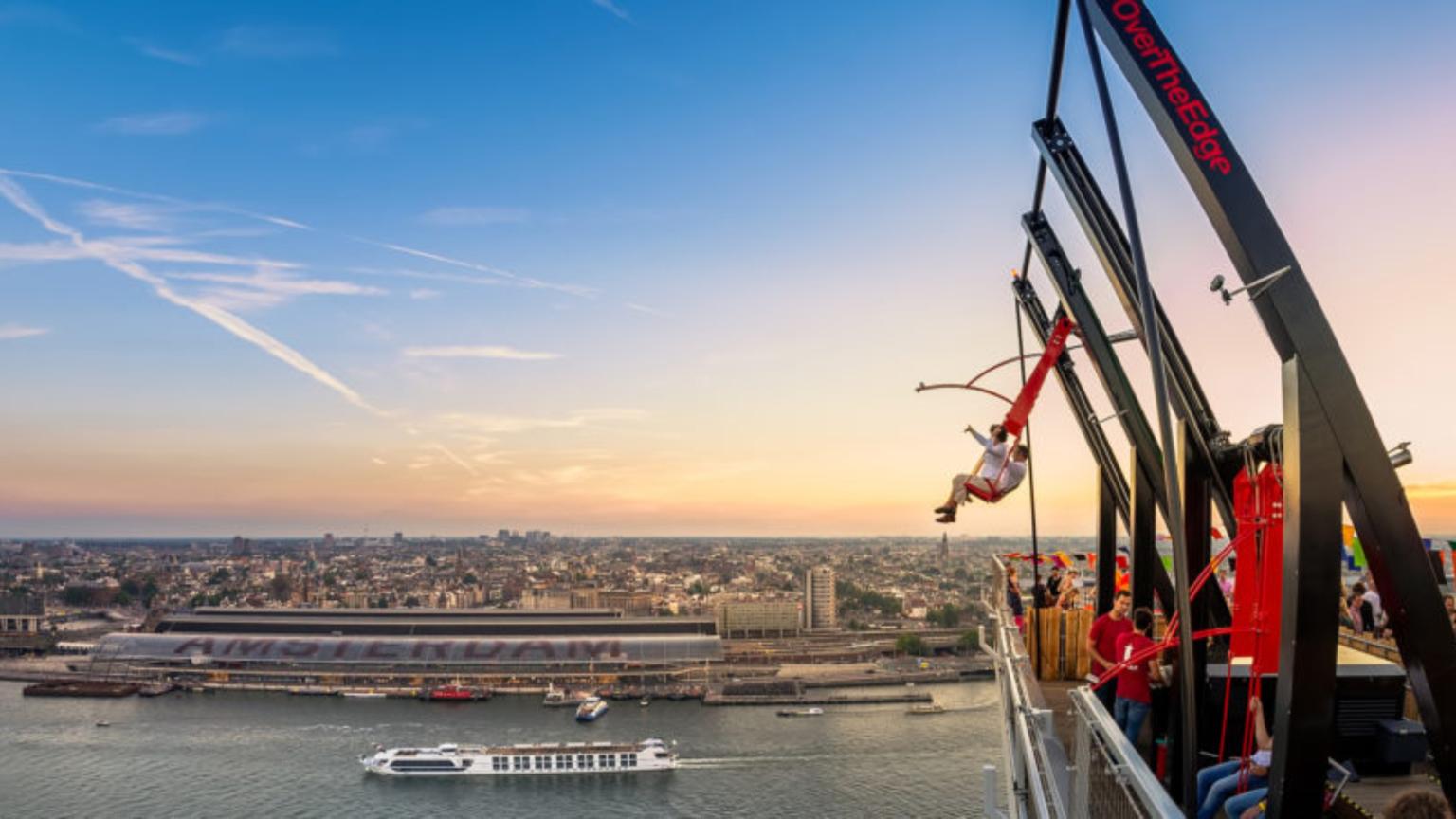 Gezin op de schommel Over The Edge bij A’DAM Lookout met uitzicht over Amsterdam.
