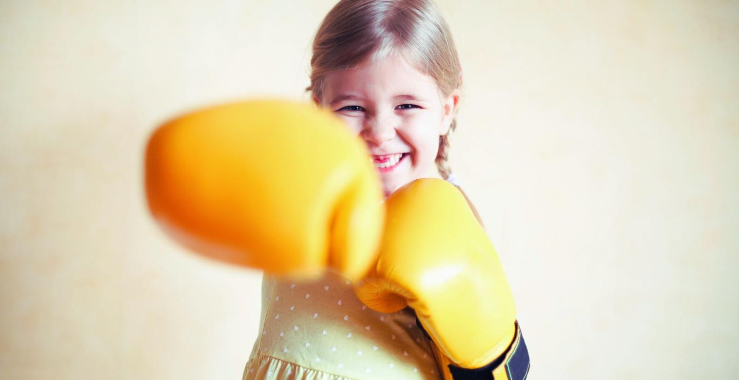 Lachend kind met gele bokshandschoenen een self-defenseles bij WOW Family Center.
