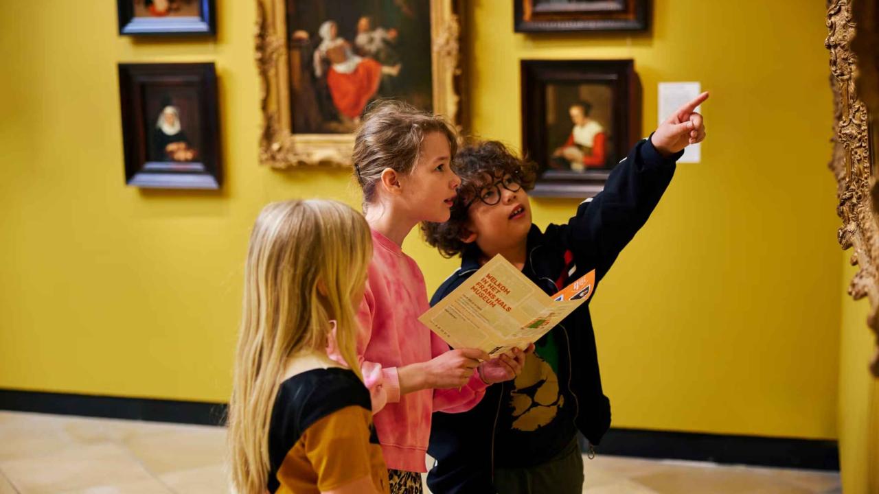 Drie kinderen volgen een speurtocht in een museum
                