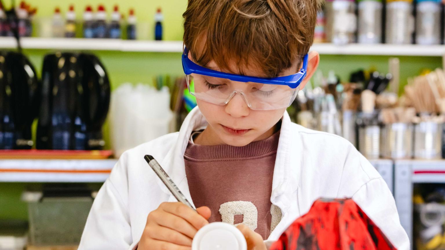 Kind met veiligheidsbril voert een creatief wetenschapsproefje uit in het lab