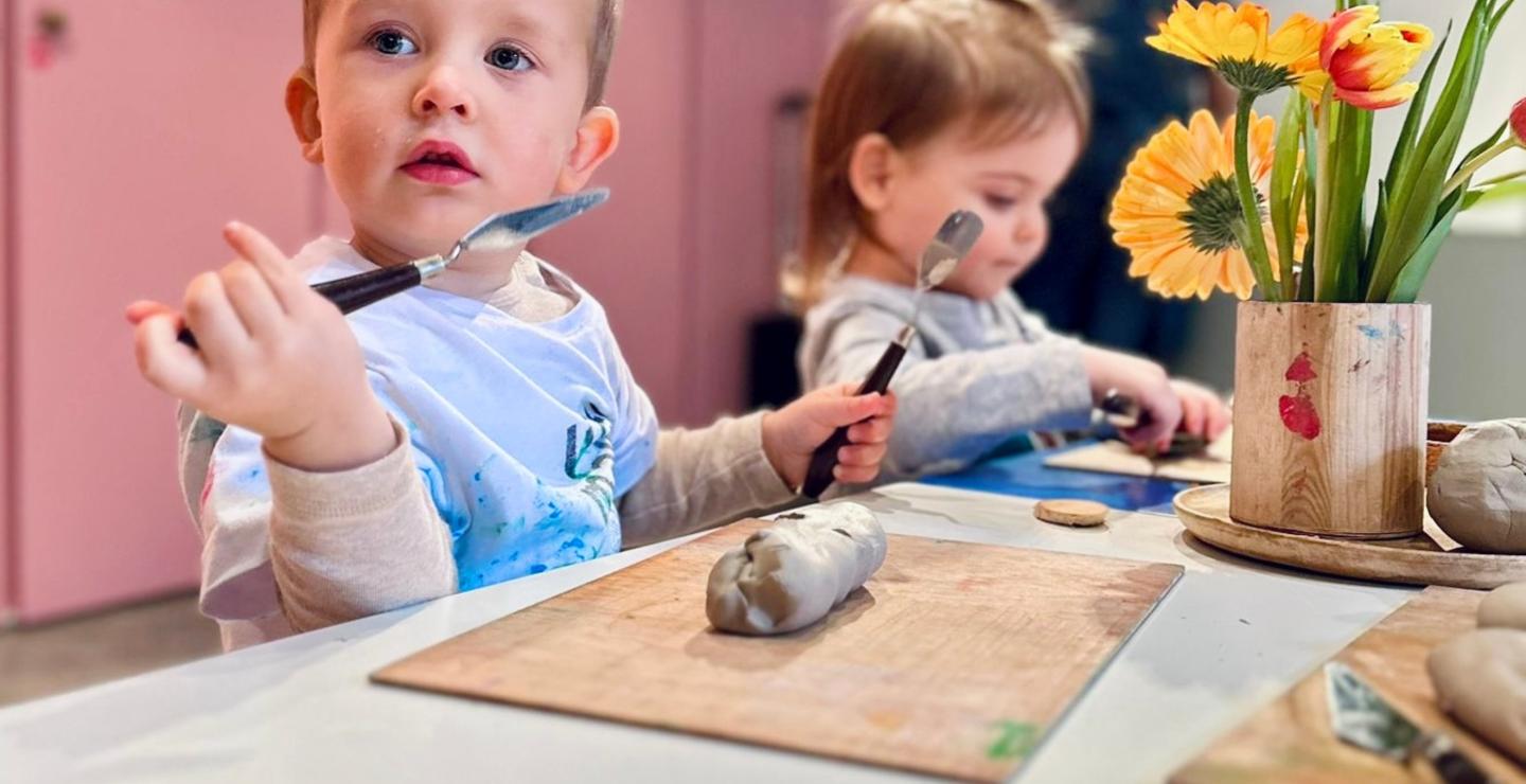 Peuters boetseren met klei en gereedschap tijdens een Montessori-geïnspireerde creatieve activiteit.